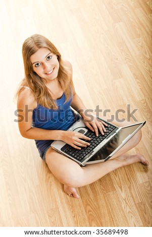 Beautiful young woman sitting on floor and working on a laptop