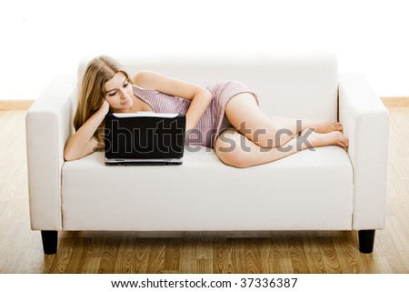 Beautiful young woman sitting on a sofa and working on a laptop