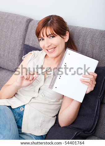 Woman sitting on couch and showing something on a notebook