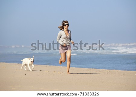 Young woman running and playing with her cute labrador retriever puppy