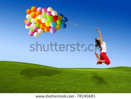 Beautiful and athletic Girl jumping with balloons on a green meadow