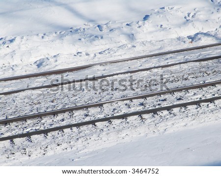 Two rail pairs surrounded with snow on a sunny day