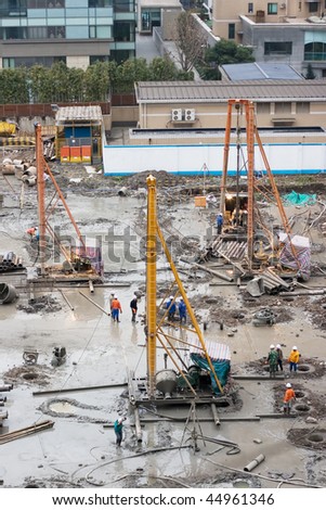A construction site on the basement phase with drilling equipment and workers on it