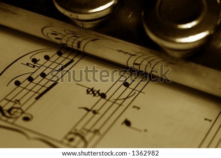 A detail of a flute resting on a sheet of music score