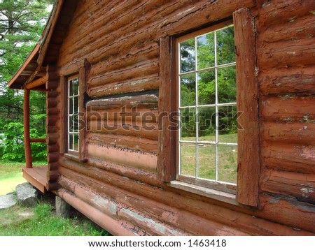 the windows of a log cabin reflecting the scenery