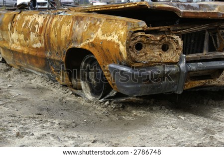 a rusty shell of an old car sitting in the dirt
