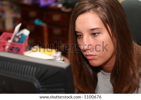 College student working at computer in messy dorm room, concentrating