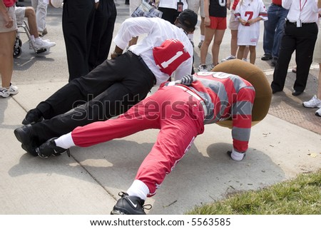Brutus and a fan do a one arm push-up before the game