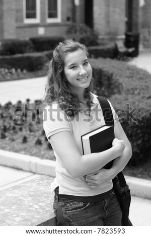Female college student on campus holding a book and computer bag