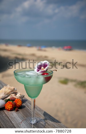 Green margarita with a cherry and flower...ocean and beach in the background