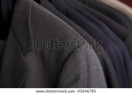 Professional men\'s suits hanging on a rack.