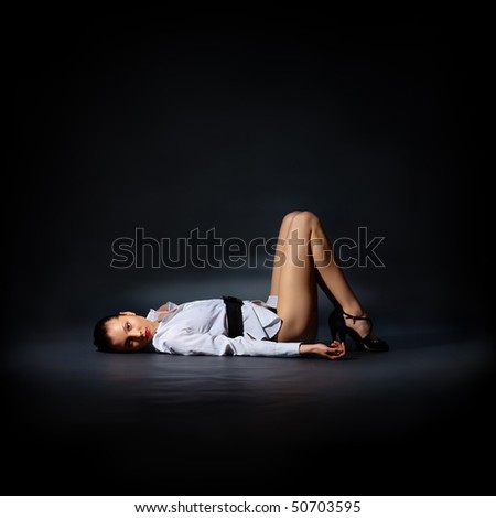 The portrait of a slim young lady in a white shirt lying on the floor