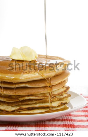 A stack of pancakes, with syrup drizzling down over the top. A dollop of butter sits on top. Country style.