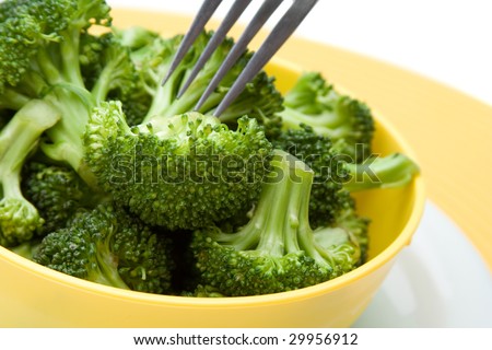 Fresh steamed broccoli florets in a bright bowl. Fork in the background.