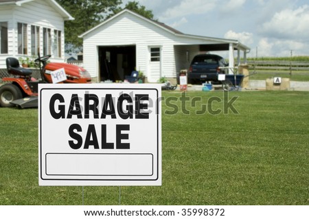 A garage sale sign with garage and items in background. Room for copy.
