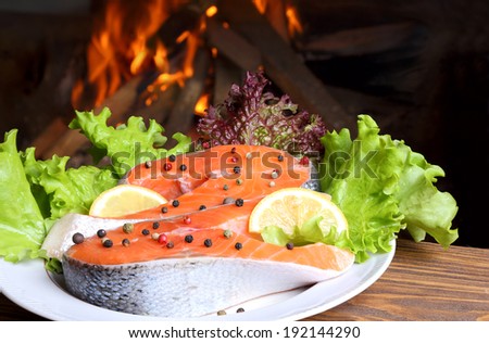Two salmon steak on a plate on the background of a burning flame