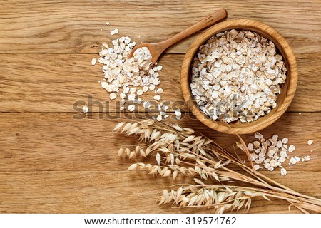 Rolled oats and oat ears of grain on a wooden table, copy space