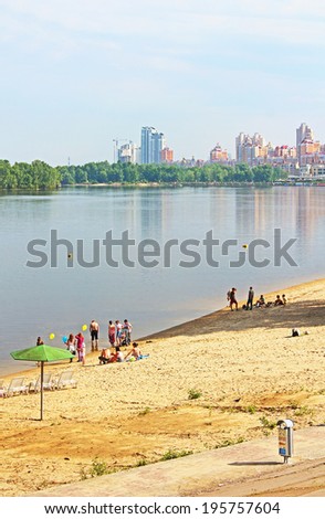 KYIV, UKRAINE - MAY 17, 2014: Unidentified people are resting on the beach of Dnipr river in Obolon district, Kyiv, Ukraine. Obolon embankment is a favorite place of people for resting in Kyiv