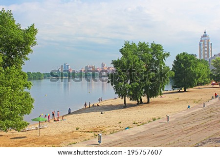 KYIV, UKRAINE - MAY 17, 2014: Unidentified people are resting on the beach of Dnipr river in Obolon district, Kyiv, Ukraine. Obolon embankment is a favorite place of people for resting in Kyiv