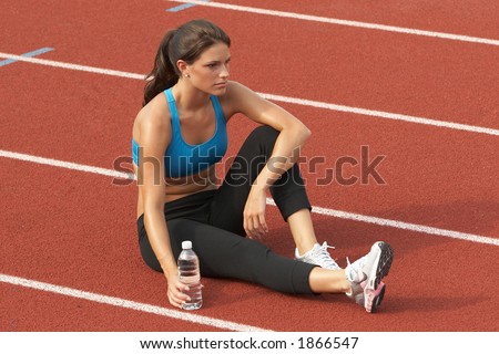 Beautiful Young Woman in Sports Bra with Water Bottle on Track Relaxing