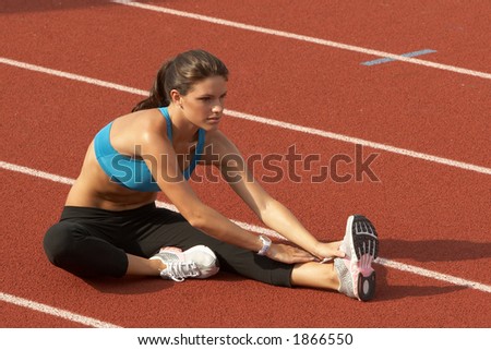 Beautiful Young Woman in Sports Bra Stretching Leg on Track