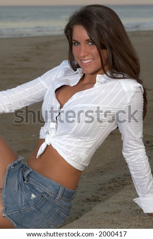 Beautiful Young Brunette Woman in White Shirt and Jean Skirt Leaning Back on Arm