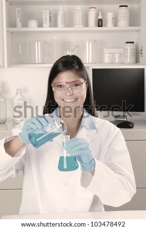 Young female lab tech pouring liquid form beaker into a flask. Horizontal format.