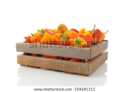 Assorted sweet peppers in a wood shipping crate. Horizontal over a white background with reflection.