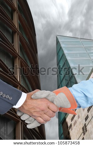 Businessman and laborer wearing a work glove handshake with modern building in the background. Management and Labor negotiation concept. Hands and sleeves only in horizontal format.