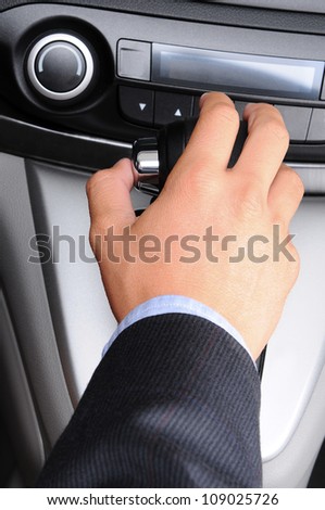 Closeup of a man\'s hand on the gear shifter of his car. Vertical Format. Man and car are unrecognizable.