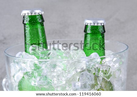 Closeup of two green beer bottles in a crystal ice bucket.
