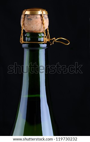 Closeup of a champagne bottle with cork and cage on a black background. Vertical Format.