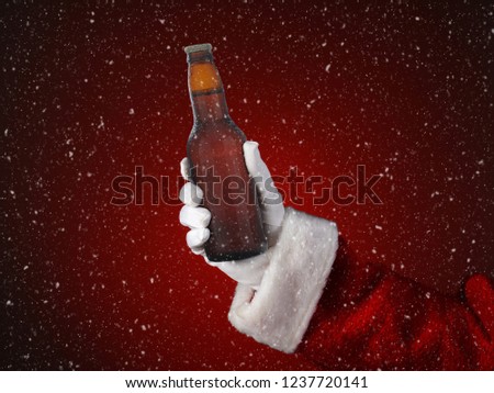 Closeup of Santa Claus holding a bottle of beer. Only hand and arm are visible. Horizontal format on a light to dark red spot background, with snow effect.