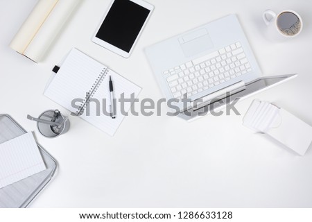 A neat white desk with objects either white or silver.  High angle shot of a business desk mock up.