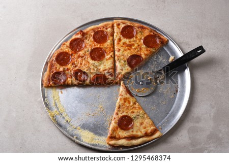 Top view of a homemade pizza on a pan with slices missing and a pizza cutter.