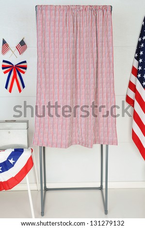 A single voting booth with American flags and bunting with a table and ballot box.