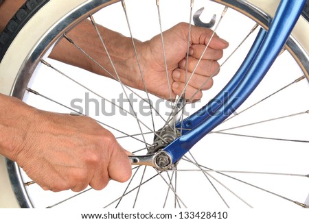 Closeup of a mans hands tightening the bolts on a bicycle wheel.