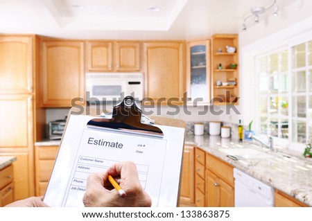 Closeup Of A Contractors Clipboard As He Writes Up An Estimate For A Kitchen Remodel. Shallow Depth Of Field With Focus On Clipboard.