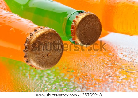 Closeup of three soda bottles on their sides with water droplets and reflection.