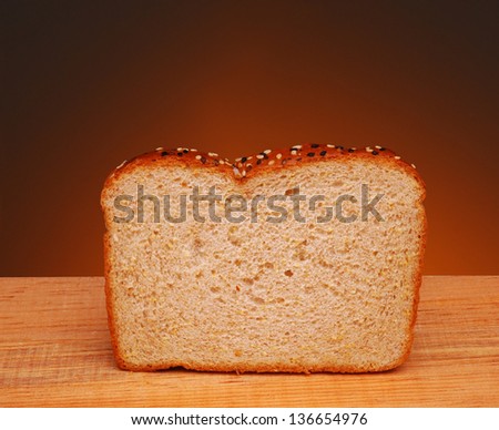 A slice of whole grain bread on a wood table and a war light to dark background.