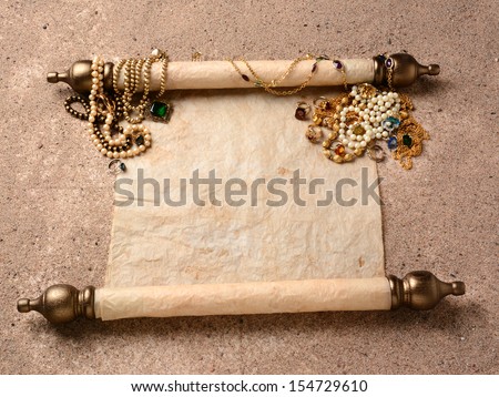 Pirates Booty. An ancient scroll laying on beach sand with jewelry scattered on it upper end. The scroll is blank ready for your treasure map or copy.
