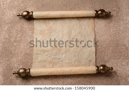 A rolled out scroll of parchment on a sand covered floor. The paper is blank ready for your copy.