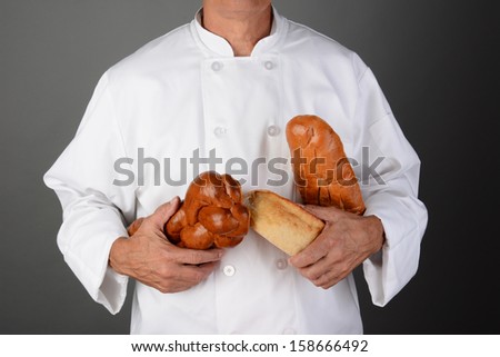 A baker with loaves of bread. Horizontal format over a light to dark gray background. Man is unrecognizable.
