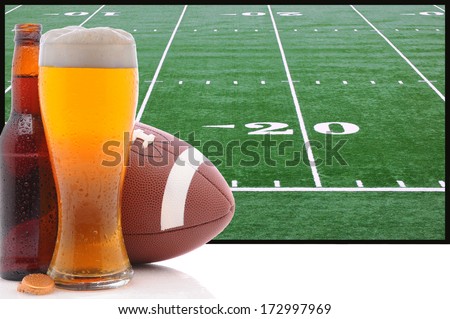 A Frothy Glass Of Beer With An American Football In Front Of A Big Screen Television. Great For Super Bowl Themed Projects.