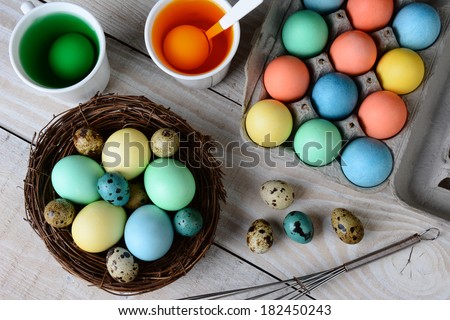 High angle view of Easter Egg dying. Dyed eggs in a nest with eggs in dye solution. Horizontal format on a rustic farmhouse style kitchen table.