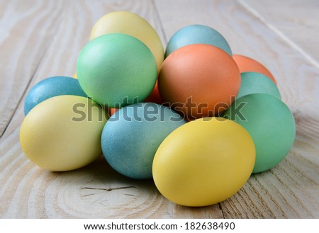 Closeup of a pile of pastel Easter Eggs on a rustic farmhouse style table. Horizontal format.