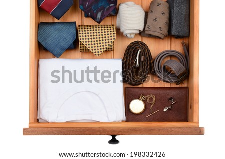 High angle shot of a dresser drawer with under shirts, belts, neck ties, socks, pocket watch and cuff links. Horizontal format isolated on white.