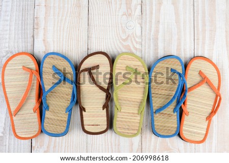 Mismatched Flip Flop sandals on a wooden deck. High angle shot of summer shoes.