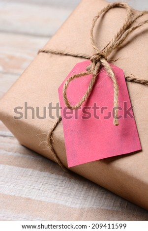 Closeup of a plain wrapped Christmas Present with a red gift tag. The tag is blank. Shallow Depth of field.