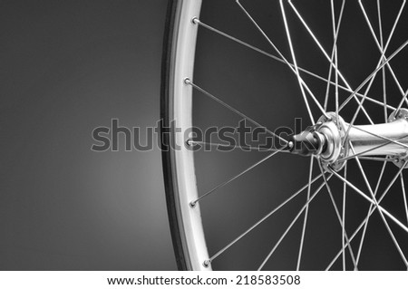 Closeup of a bicycle wheel on a light to dark black and white background. Only half of the wheel is shown. Horizontal format with copy space.